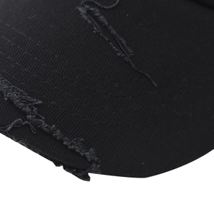 Detailed close-up of distressed brim on washed black cotton baseball cap with ripped effects