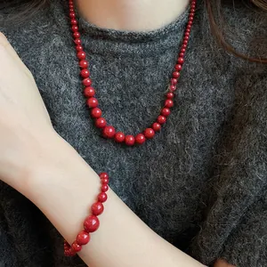 Parure collier et bracelet en perles rouges portée par un mannequin en pull