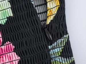 Detail shot of hidden back zipper on floral print smocked fabric with colorful patterns