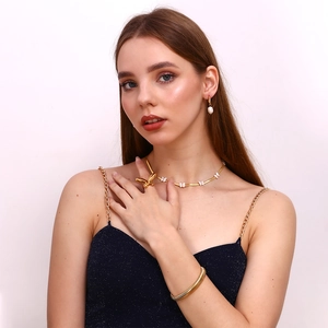 Close-up of elegant gold butterfly necklace and pearl earrings on female model