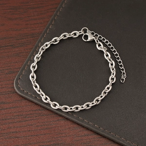 Detail of silver stainless steel chain bracelet with lobster clasp on leather background