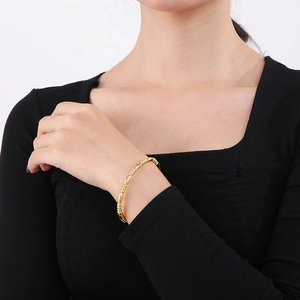 Detailed view of an 18K gold-plated bamboo-style stainless steel bangle on a wrist