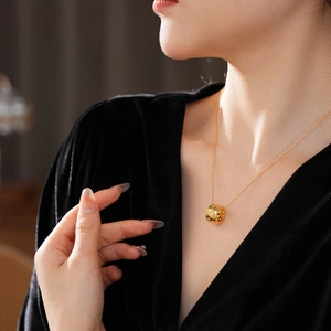 Dettaglio macro di una collana in titanio dorato con pendente circolare e zirconi luminosi
