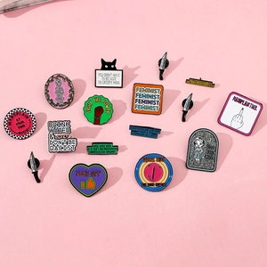 Close-up of assorted enamel pins with feminist slogans on a pink background