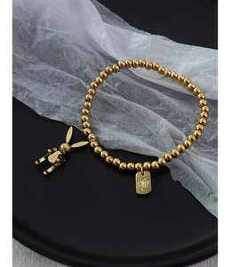 Makrodetail der goldenen Perlenarmband mit Hasenanhänger und graviertem Quadrat