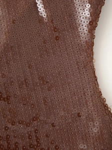 Macro shot of high-density bronze sequins on mesh fabric for a party evening dress