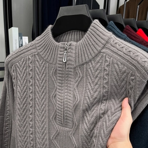 Detail of dark grey cable knit sweater featuring a metal half-zip and ribbed stand collar