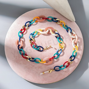 Colorful acrylic link eyeglass chain with gold metal clasps on pink velvet display