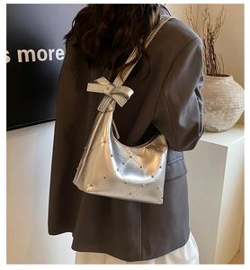 Détail du sac demi-lune argenté avec matelassage en losange et nœud sur la bandoulière