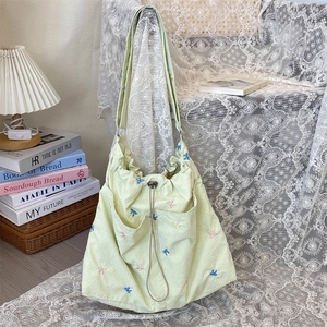 Detail of light green plaid canvas bag featuring delicate floral butterfly embroidery