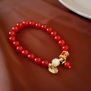 Gros plan d'un bracelet en perles rouges avec pendentif Fu doré et perle émaillée