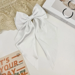 Elegant white satin oversized bow hair clip with long ribbons on minimalist background