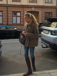 Street style view of a brown plaid wool jacket paired with jeans and high boots