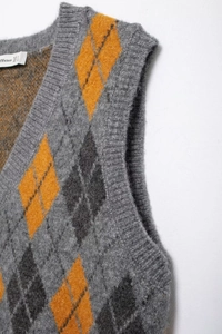 Macro detail of V-neck argyle knitted vest with gray, yellow and dark gray pattern texture
