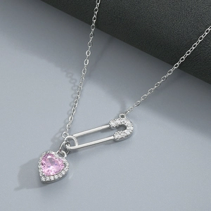 Macro view of silver safety pin necklace featuring a sparkling pink heart zircon pendant