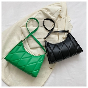 Detail of green and black quilted shoulder bags with gold zippers on tweed fabric