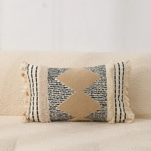 Detail of bohemian lumbar pillow with beige diamond tufting and pink tassel accents