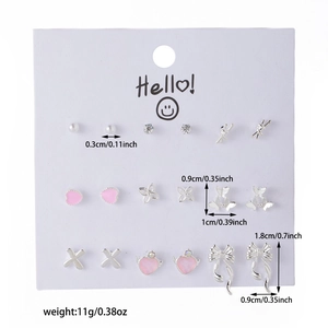 Detailed view of nine pairs of silver cherry and heart stud earrings on white card