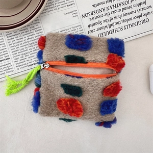 Macro shot of khaki plush pouch featuring colorful pom-poms and bright orange zipper