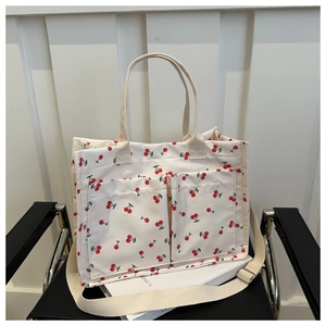 Detail shot of the cream canvas tote bag with red cherry print and large front pockets