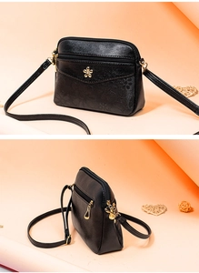 Close-up detail of black leather crossbody bag with chic gold floral clasp and strap.