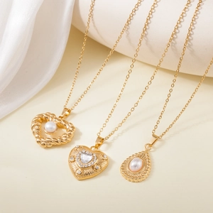 Close-up of gold stainless steel necklaces with heart and teardrop pearl pendants