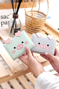 Close-up of mint green and light grey trifold wallets with cute cartoon pig design