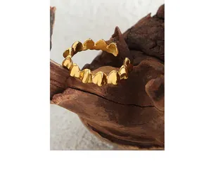 Detailed close-up of a gold-plated adjustable heart-shaped ring on a natural wooden base