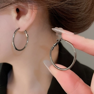 Detailed view of large gunmetal hoop earrings with smooth metallic finish on model