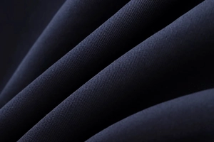 Macro texture of pleated dark blue fabric showing high-density weave and matte finish