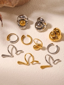 Vue macro de boucles d'oreilles et bagues d'oreilles dorées et argentées sur fond sable