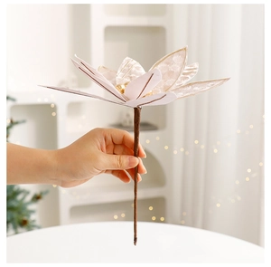 Detail of 25cm cream white Christmas flower with gold edges held in a festive home setting