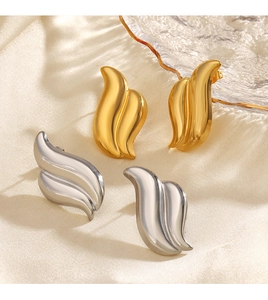 Detailed view of asymmetric wing earrings in gold and silver finish on silk