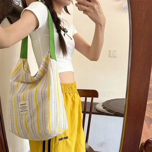 Selfie miroir montrant un grand sac fourre-tout à rayures colorées et anses vertes