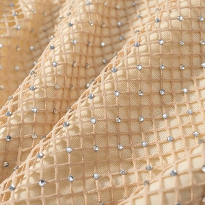 Macro shot of apricot mesh fabric with sparkling silver rhinestones for elegant dresses