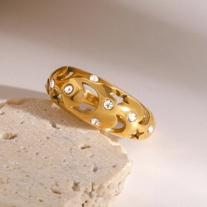 Close-up of golden hollow ring featuring moon and star patterns with white stones