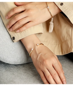 Close-up of dual zircon open cuff bracelets in 18K gold plating on a model wrist