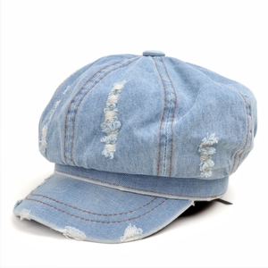 Detailed close-up of light blue distressed denim newsboy cap with frayed hole design