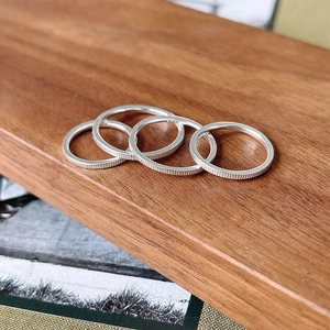 Macro shot of 925 sterling silver rings with vertical coin edge texture on wood