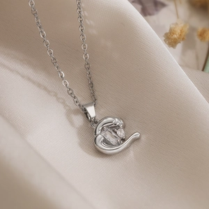 Irregular heart pendant necklace with cubic zirconia on elegant beige silk fabric