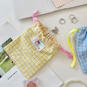 Detail of yellow plaid drawstring bag with cute woven label on a white desktop