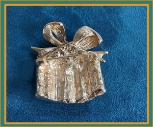 Detail view of the golden metal gift box brooch back with a secure safety pin fastener
