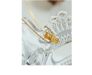 Detailed shot of yellow faceted crystal pendant with gold chain on glass edge