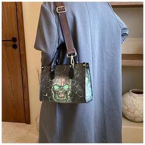 Detail of skull print tote with wide fashion strap worn on a grey wool coat