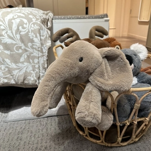 Plush elephant toy and small animal friends resting in a cozy wicker basket