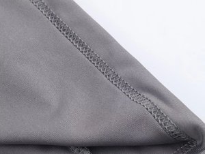 Detailed macro view of dark grey knitted fabric and precise overlock stitching finish