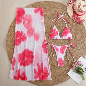 Detailed flat lay of a floral bikini set with a matching mesh sarong on a straw mat