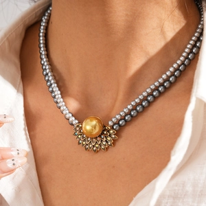 Collana a due strati in perle di vetro con un pendente dorato vintage e cristalli brillanti