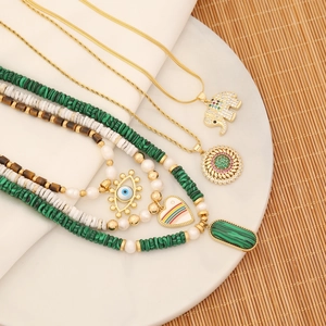 Layered gold necklace featuring natural stones, elephant charm, and evil eye pendant on a tray