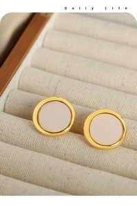 Macro detail of gold round geometric earrings with cream shell inlay in jewelry box